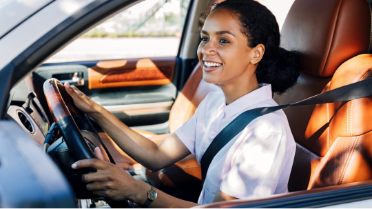 Happy young woman driving a clean car