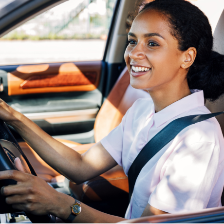 Happy young woman driving a clean car